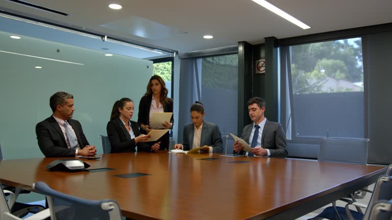Female lawyer handing out binders to her colleagues ready to start a meeting at the board room