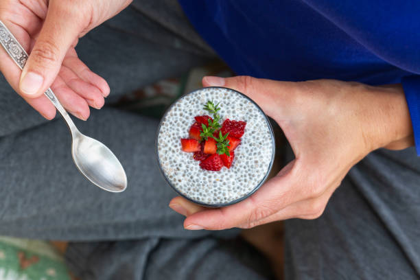 Female hands holding chia pudding with fresh strawberries for breakfast Vegan healthy eating and dieting food concept. Female hands holding chia pudding with fresh strawberries for breakfast eating chia seeds stock pictures, royalty-free photos & images