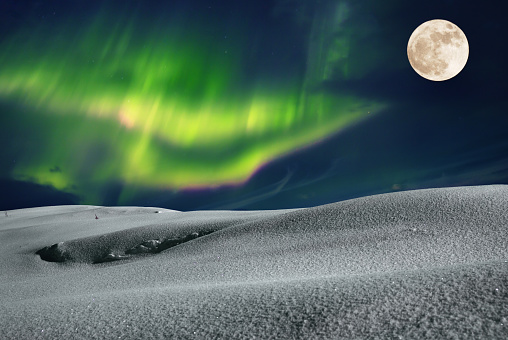 Aurora borealis over frosty winter night field with fool moon in the sky