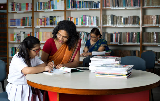 istock Teacher helping schoolgirl studying in library 1350889729