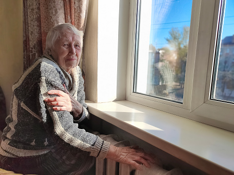 Freezing old people in Europe. The senior woman in bed at home. Payment for heating in winter. The gas crisis has led to an increase in gas prices
