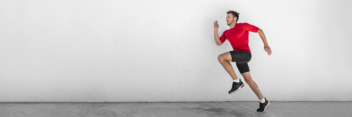 Sprint run man runner running doing jump training outdoor sprinting at gym. Fit healthy active lifestyle. Male athlete hiit high intensity interval cardio workout. Banner panorama wall background.