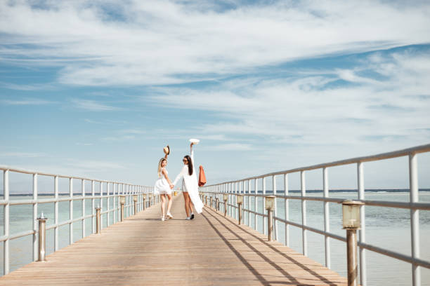 istock Two happy young women walking on pier and looking back 1350892840