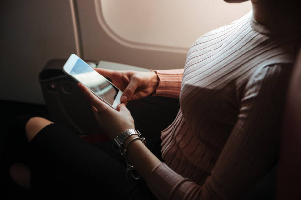 istock Cropped image of woman using phone in aircraft 1350894071