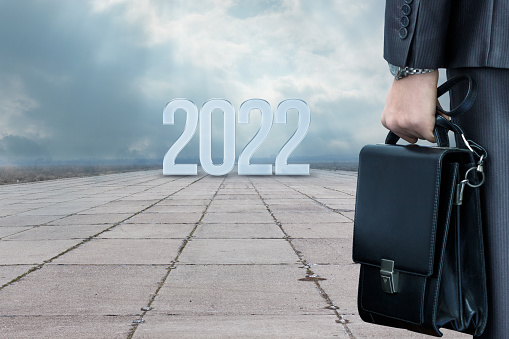Business man are standing with a briefcase in their hands on the road before the new year 2022.