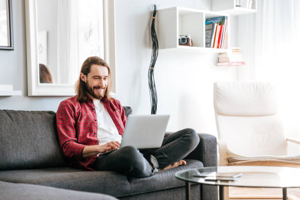 istock Happy man sitting on sofa and using laptop at home 1350896518