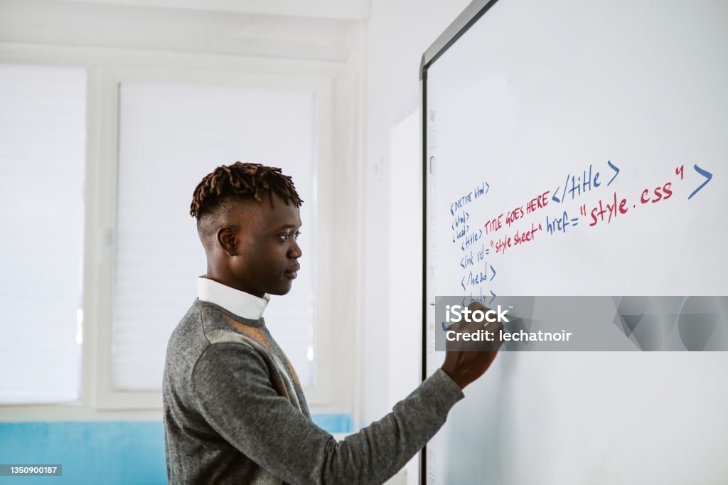 IT teacher writing on the whiteboard in the classroom Teacher writing on the whiteboard in the high school classroom Coding Stock Photo