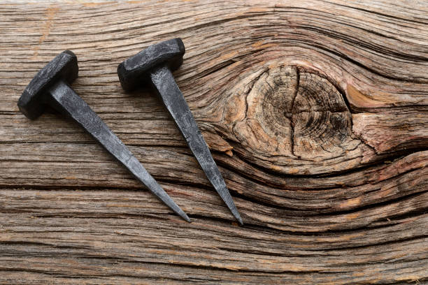 dos clavos forjados de hierro sobre un fondo de madera - foto de stock