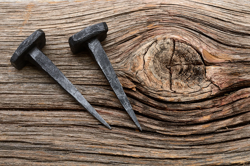 two iron forged nails on a wooden background