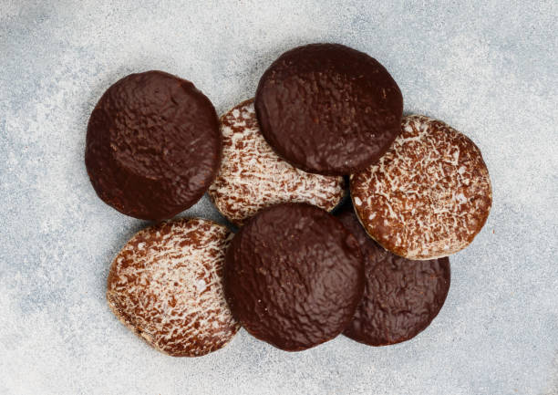 panes de jengibre de núremberg con frutos secos (almendras, avellanas, nueces) en chocolate y glaseado de azúcar. lebkuchen. delicias tradicionales de navidad y año nuevo. enfoque selectivo, vista superior - anise baked biscuit brown fotografías e imágenes de stock