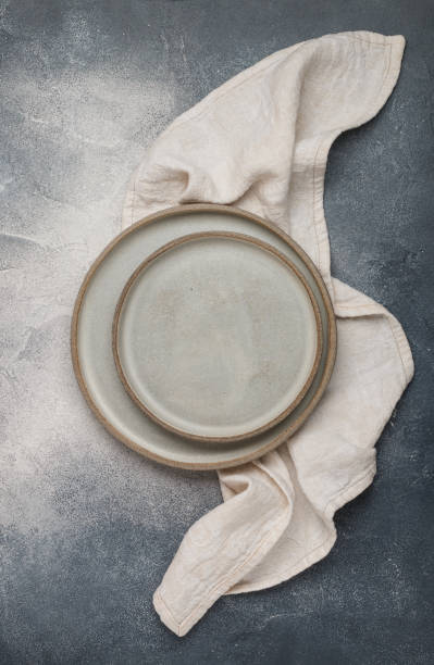 istock empty grey plates and linen napkin on grey concrete or stone table. Cooking background. Rustic style. Selective focus. Top view, copy space 1350903389