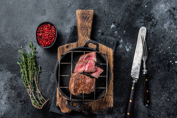 istock Grilled fillet mignon beef steak on a grill. Black background. Top view 1350905655