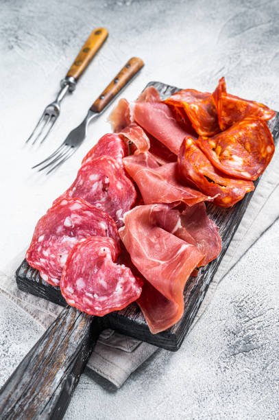 istock Assorted meat appetizers - salami, jamon, choriso sausages. White background. Top view 1350906501