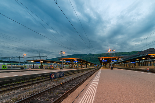 Wide-angled view over the platforms and tracks of the station. when the sky is cloudy, in the background the foot of the jura mountains. 05/13/2021 - 2502 Biel Bienne, canton Bern, Switzerland