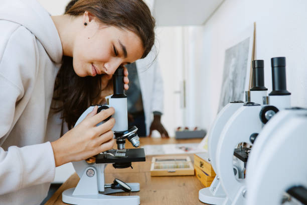 Female high school student at the biology - science class Female high school student at the biology - science class, looking through the microscope. biology class stock pictures, royalty-free photos & images