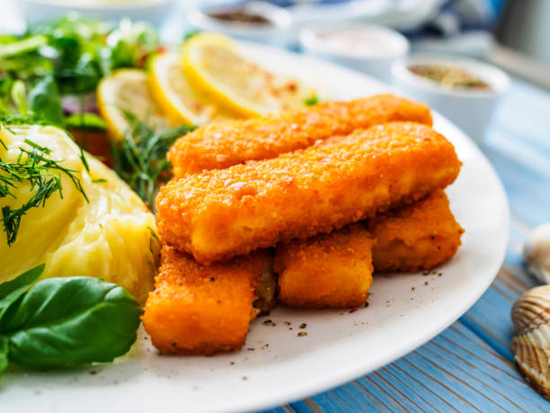 Fried fish sticks with potato puree and fresh vegetable salad on wooden table Fried fish sticks with potato puree and fresh vegetable salad on wooden table fish stick stock pictures, royalty-free photos & images