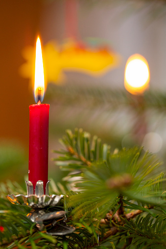 four red burning candelights and fir cones for advent or christmas decoration on blurred shiny background with copy space for holiday greetings