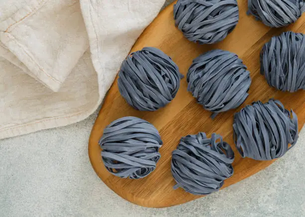 Photo of Raw organic wheat blue noodles with anchana flowers. The concept of a healthy and sporty lifestyle. butterfly pea flowers. Thai cuisine. Selective focus, Top view and Copy Space