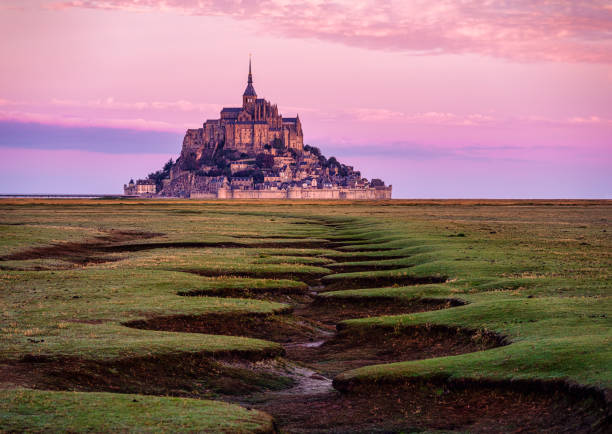 le mont saint michel au lever du soleil avec marée basse et couleurs roses normandie france - tradition française photos et images de collection