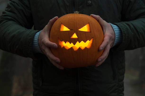 istock Halloween pumpkin head in male hands at night 1350912380
