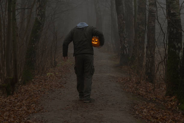 istock Headless man with Halloween pumpkin in foggy forest 1350912461