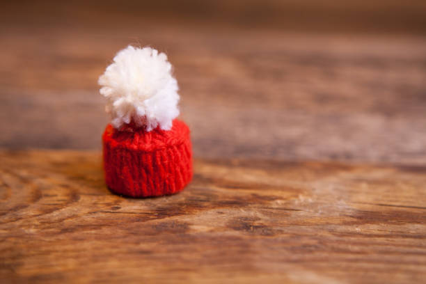 Mini knitted Santa Claus hat on wooden background with place for your text.