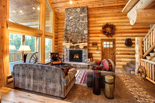 A luxurious living room, with a fireplace and comfortable furnishings, in a modern log cabin in the mountains.