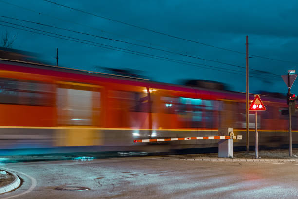istock Fast moving red train passing grade crossing with barriers down and red light flashing. No cars are visible, only blur of a train over the crossing, 1350915082