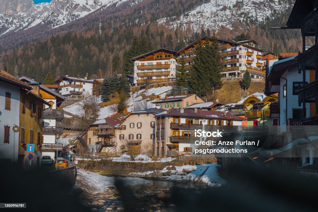 Houses and hotels in Moena, a city in italian Val di Fassa on a sunny winter day rising over the river in the centre Blue Stock Photo