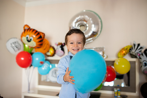 Two year old boy holding birthday balloon