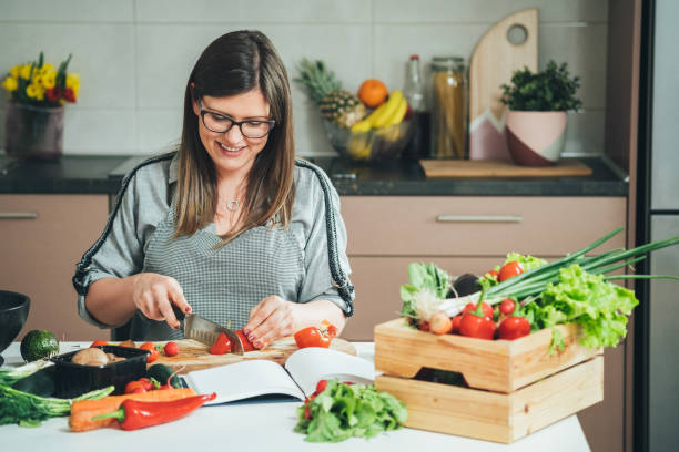 istock Happy Woman Cutting Organic Pepper on Cutting Board at Kitchen Table 1350918363