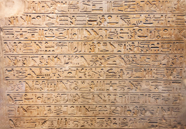 Ancient Egyptian writings, hieroglyphs and signs on a stone slab close-up. Historical Egyptian symbols, figures and symbols as text on the wall.