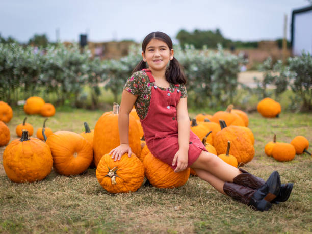 kubanisch-amerikanisches kleines mädchen posiert zwischen kürbissen in florida - pumpkin child little girls pumpkin patch stock-fotos und bilder