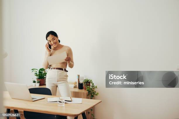 Cheerful Business Woman Analyzing Document And Talking On Mobile Phone Stock Photo - Download Image Now