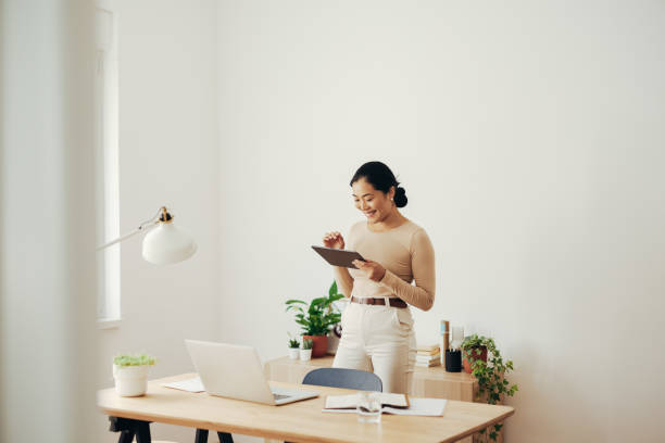 istock Cheerful Business Woman Using Digital Tablet at Home 1350926656