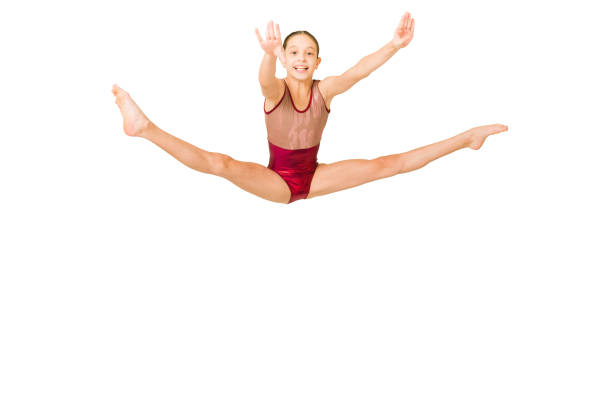 Cheerful girl enjoying her training Excited sporty gymnast smiling while jumping and doing a leg split. Cheerful girl performing on a sports competition leotard stock pictures, royalty-free photos & images