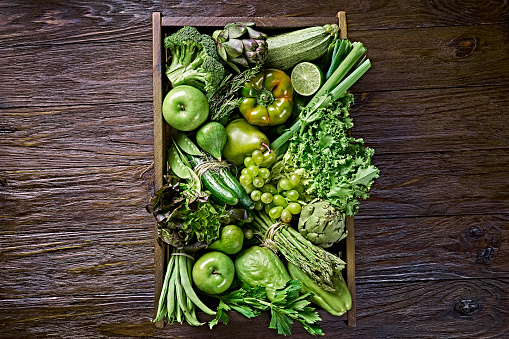 Table top view background of a variation green vegetables for detox and alkaline diet. Set in a crate on a wooden rustic table with a frame