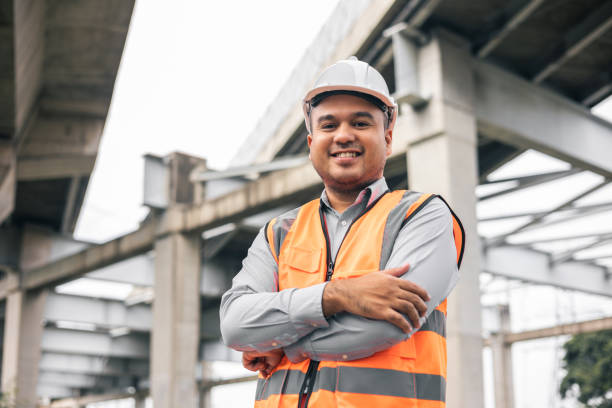 istock Asian engineer handsome man or architect looking construction with white safety helmet in construction site. Standing at highway concrete road site. 1350964435