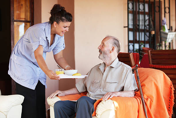 carer bringing meal to senior carer bringing meal to senior man in residential home meals on wheels photos stock pictures, royalty-free photos & images