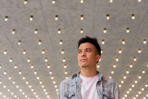 istock Low angle view portrait of handsome young man thinking outdoors in city 1350967358
