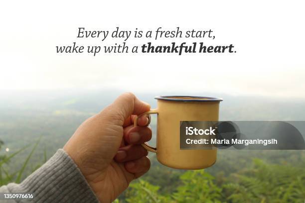 Person Holding Yellow Cup Of Tea Or Coffee In Hand Against Mountain View With A Morning Thankful Inspirational Message Stock Photo - Download Image Now
