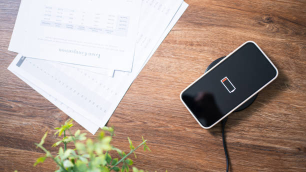istock Charging mobile phone battery with wireless charging device in the table. Smartphone charging on a charging pad. Mobile phone near wireless charger Modern lifestyle technology concept. 1350984041