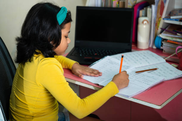 istock A cute little girl doing homework using laptop and smartphone. 1350986042