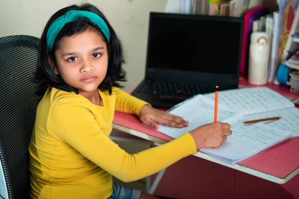 istock A cute little girl doing homework using laptop and smartphone. 1350986043