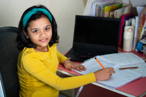 istock A cute little girl doing homework using laptop and smartphone. 1350986058