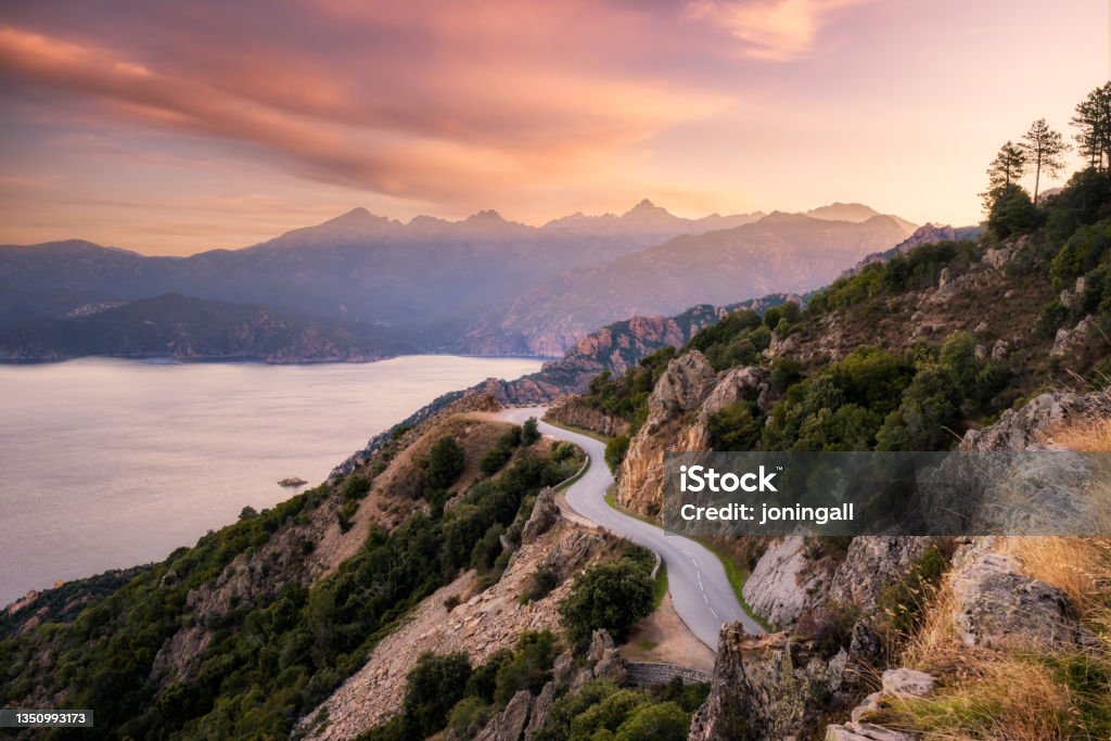 winding coast road in Corsica The D824 road winding its way along the coast from Capu Rossu towards Piana on the west coast of Corsica as the early  morning sun lights up the distant mountains Corsica Stock Photo