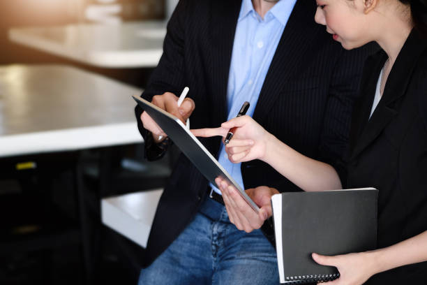 istock Consulting, female advisor pointed to company financials documents to restructure profitability of male entrepreneurs. 1350997188
