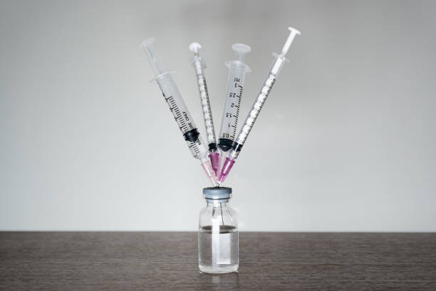 A vaccine vial with 4 syringes. A vaccine vial with 4 syringes. A fourth dose Covid-19 vaccine booster shot concept. dose stock pictures, royalty-free photos & images