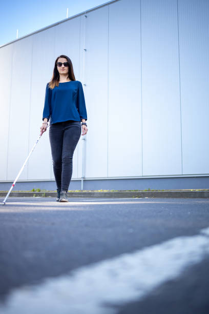 istock Blind woman walking on city streets, using her white cane 1350999365