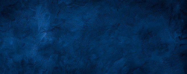 Dark blue rough grainy stone or concrete wall texture background.